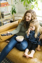 Mother and daughter with bowl of popcorn watching movie