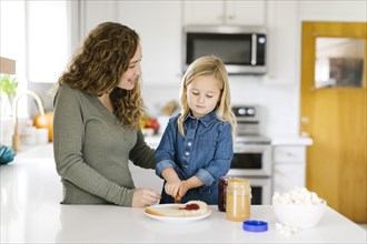 Woman making peanut butter and jelly sandwich with her daughter