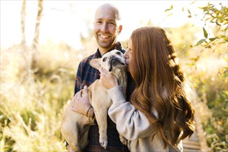 Couple with pet French bulldog in forest
