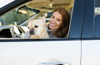 Smiling woman and pet French bulldog in car window