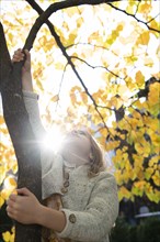 Girl climbing tree during autumn