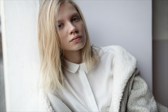 young woman in wool coat leaning against wall