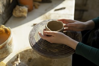 Hands of woman molding clay on potter's wheel