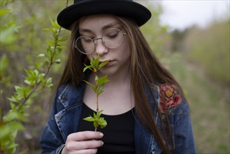 young woman smelling leaves on twig