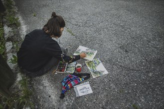 young woman painting mountains on road