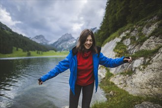 Smiling young woman in blue jacket by lake