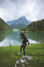 young woman balancing on rock by lake