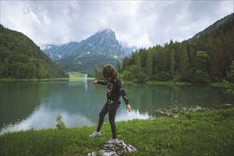 young woman balancing on rock by lake