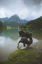 young woman crouching by lake