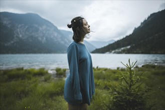 young woman in blue sweater by lake