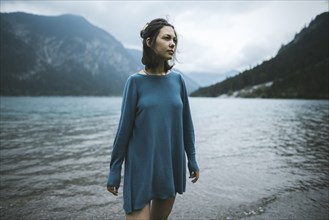 young woman in blue sweater by lake