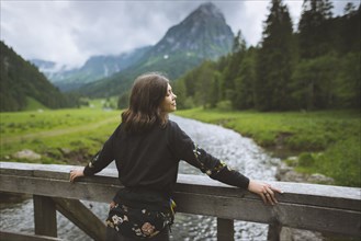 young woman leaning on railing by river