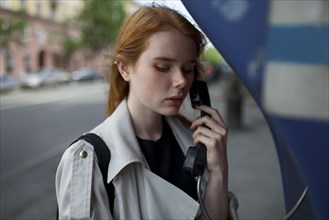 young woman using public phone
