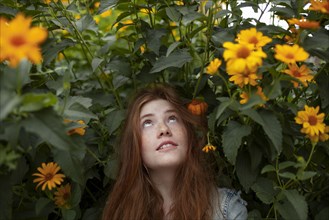 Teenage girl by bush with orange flowers