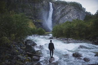 young man standing by waterfall
