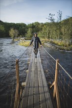 young man walking over wooden bridge