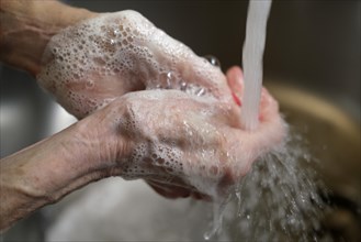 Close-up of senior woman's hands being washed