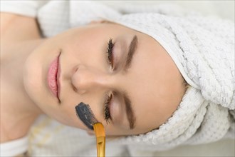 Face mask being applied on woman's face at spa
