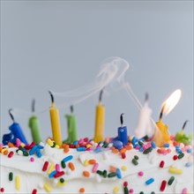 Extinguished birthday candles on cake - one still burning