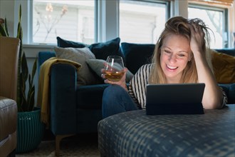 Relaxed woman with wine looking at tablet at home