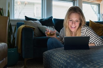 Relaxed woman with wine looking at tablet at home