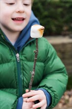 Boy watching roasted marshmallow on stick