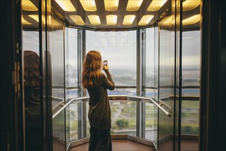 Belarus, Minsk, Woman standing in transparent elevator