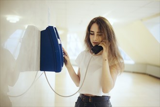 Young woman using payphone