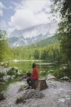 Germany, Bavaria, Eibsee, Woman sitting by Frillensee lake