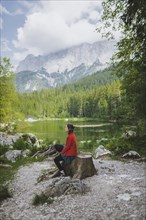 Germany, Bavaria, Eibsee, Woman sitting by Frillensee lake