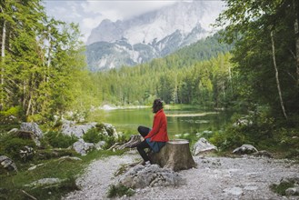 Germany, Bavaria, Eibsee, Woman sitting by Frillensee lake