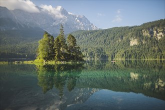 Germany, Bavaria, Eibsee, Distant view of woman paddleboarding on the lake Eibsee in Bavarian Alps at sunrise