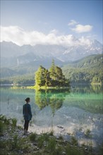 Germany, Bavaria, Eibsee, Young woman standing at shore of Eibsee lake in Bavarian Alps