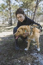 Young woman petting dog from animal shelter while walking in forest