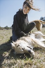 Young woman playing on grass with dog from animal shelter