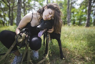 Young woman hugging dog from animal shelter in forest