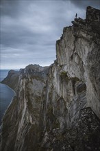 Norway, Senja, Man standing on the edge of steep cliff on top of Segla mountain