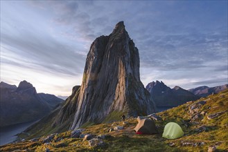 Norway, Senja, Man and two tents near Segla mountain at sunset