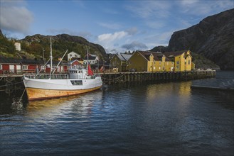 Norway, Lofoten Islands, Nusfjord, Fishing boat in dock in traditional fishing village