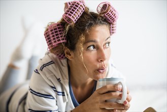 Woman with hair curlers holding mug