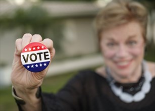 Smiling woman holding vote button