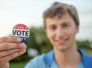 Smiling man holding vote button