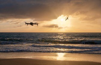 Drone flying over beach at sunset
