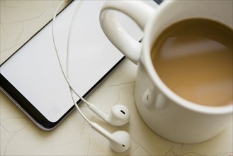 Earphones, smart phone and cup of coffee