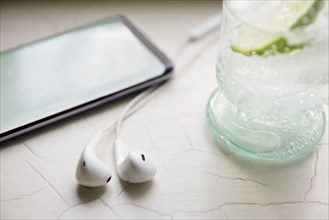 Earphones, smart phone and glass of seltzer water