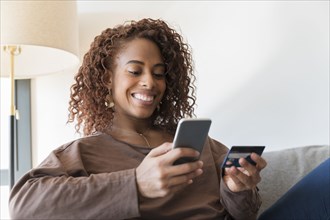 Smiling woman holding credit card and smart phone