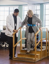 Doctor helping senior woman walk down steps