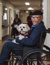 Smiling senior man holding dog in wheelchair