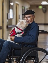 Senior man holding dog in wheelchair