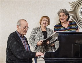 Senior women singing with senior man playing piano